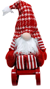 Red Gnome Sitting on Red Sled Holding a Christmas Gift